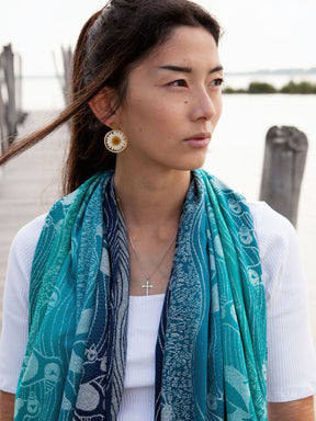 Woman wearing a teal shawl on a pier. 