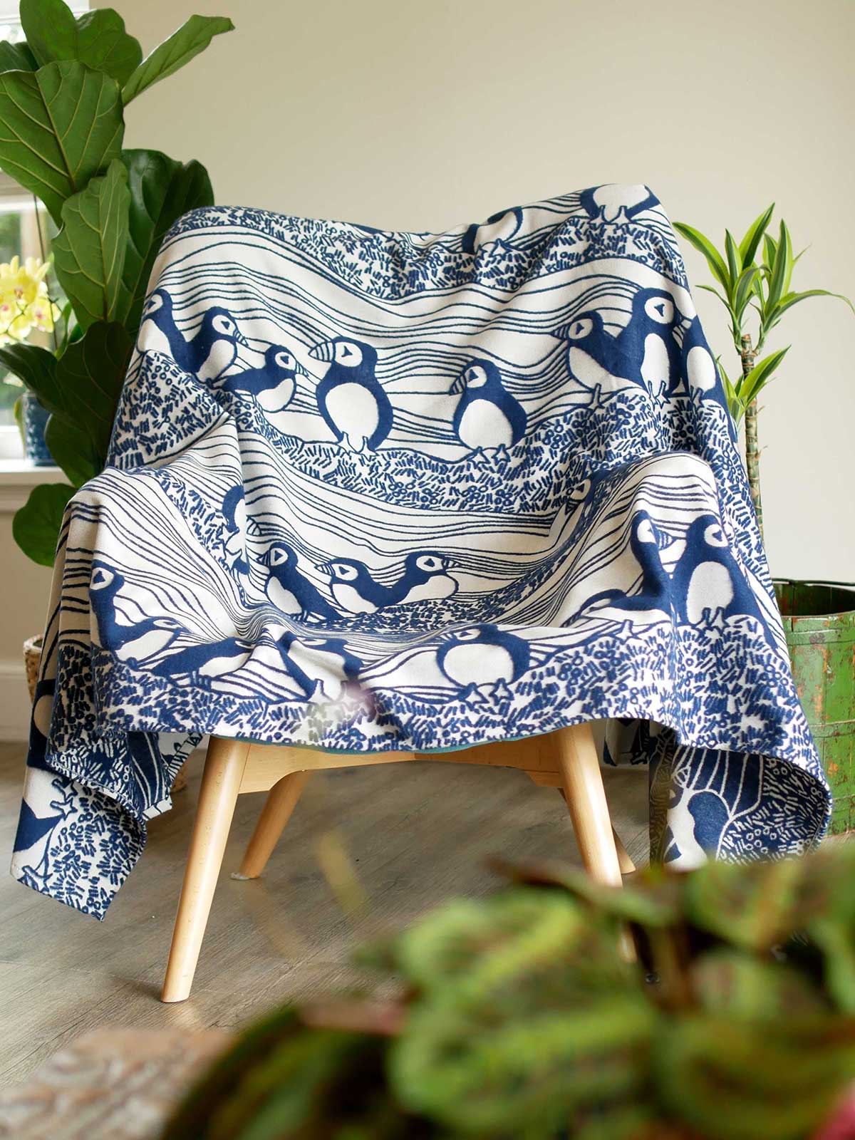 Lightweight blanket with puffin pattern laid over a chair