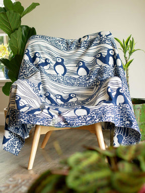 Lightweight blanket with puffin pattern laid over a chair