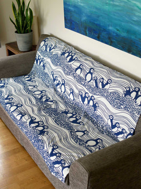 Lightweight blanket with puffin pattern laid over a sofa