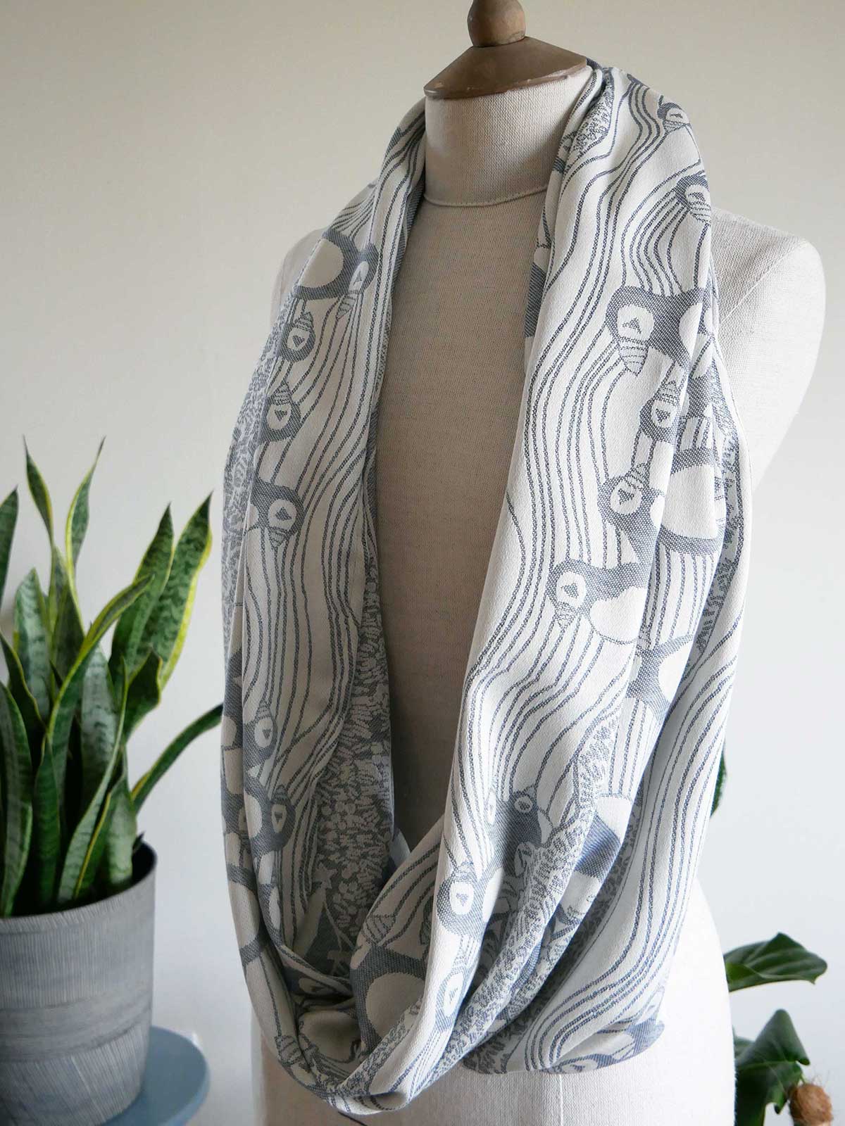 Ink blue patterned infinity scarf on a mannequin with a plant in the background