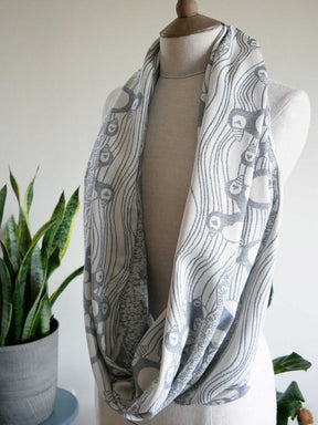 Ink blue patterned infinity scarf on a mannequin with a plant in the background