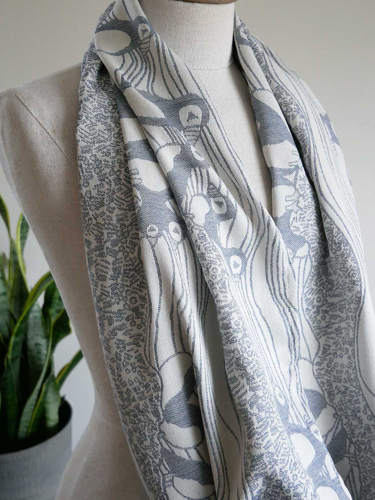 Blue and white patterned scarf on a mannequin with a plant in the background