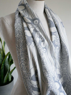 Blue and white patterned scarf on a mannequin with a plant in the background