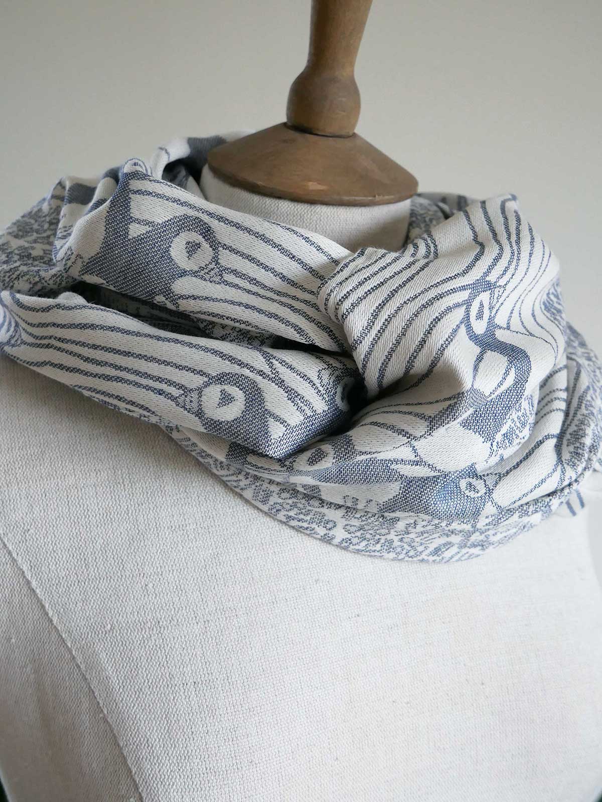 Scarf with bird pattern draped over a wooden stand on a neutral background