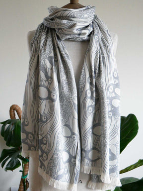 Mannequin wearing a puffin patterned scarf with green plants in the background