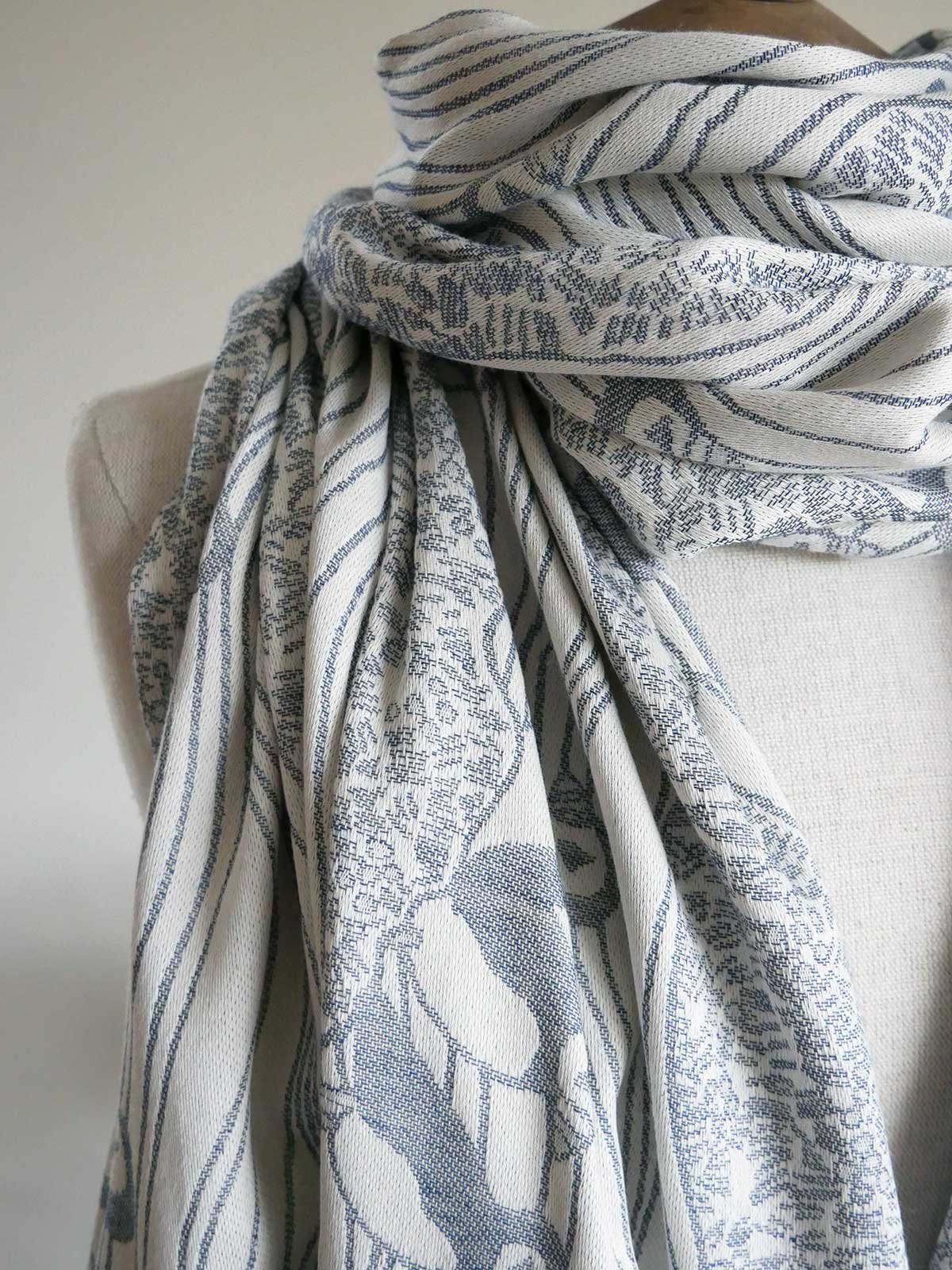 White scarf with blue puffins draped over a mannequin against a plain background