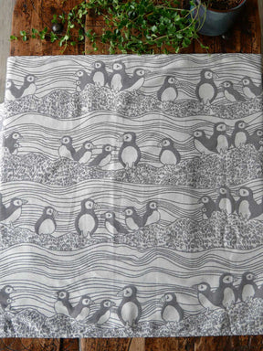 Textile with puffin pattern on a wooden surface