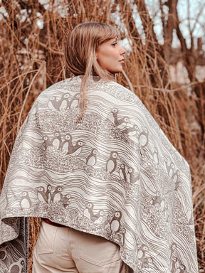 Person wearing a patterned shawl in front of dried plants