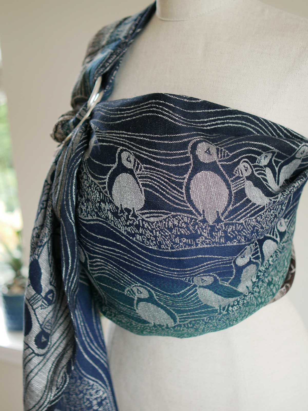 Side view of blue and green ring sling with puffin design on a mannequin.