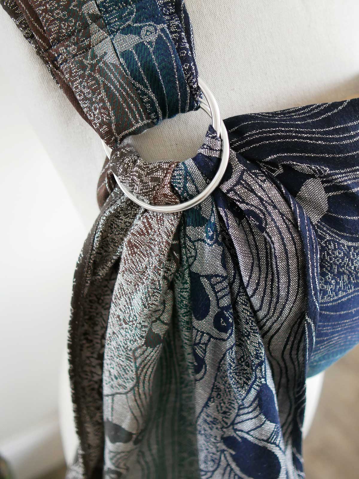 Close up of a silver ring on a blue ring sling on a mannequin