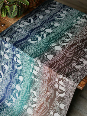 Blue, green and brown fabric with puffin design on a wooden table.