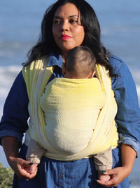 Woman with a baby in a yellow woven wrap.