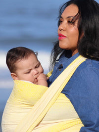Close up of a woman with a baby in a yellow woven wrap.