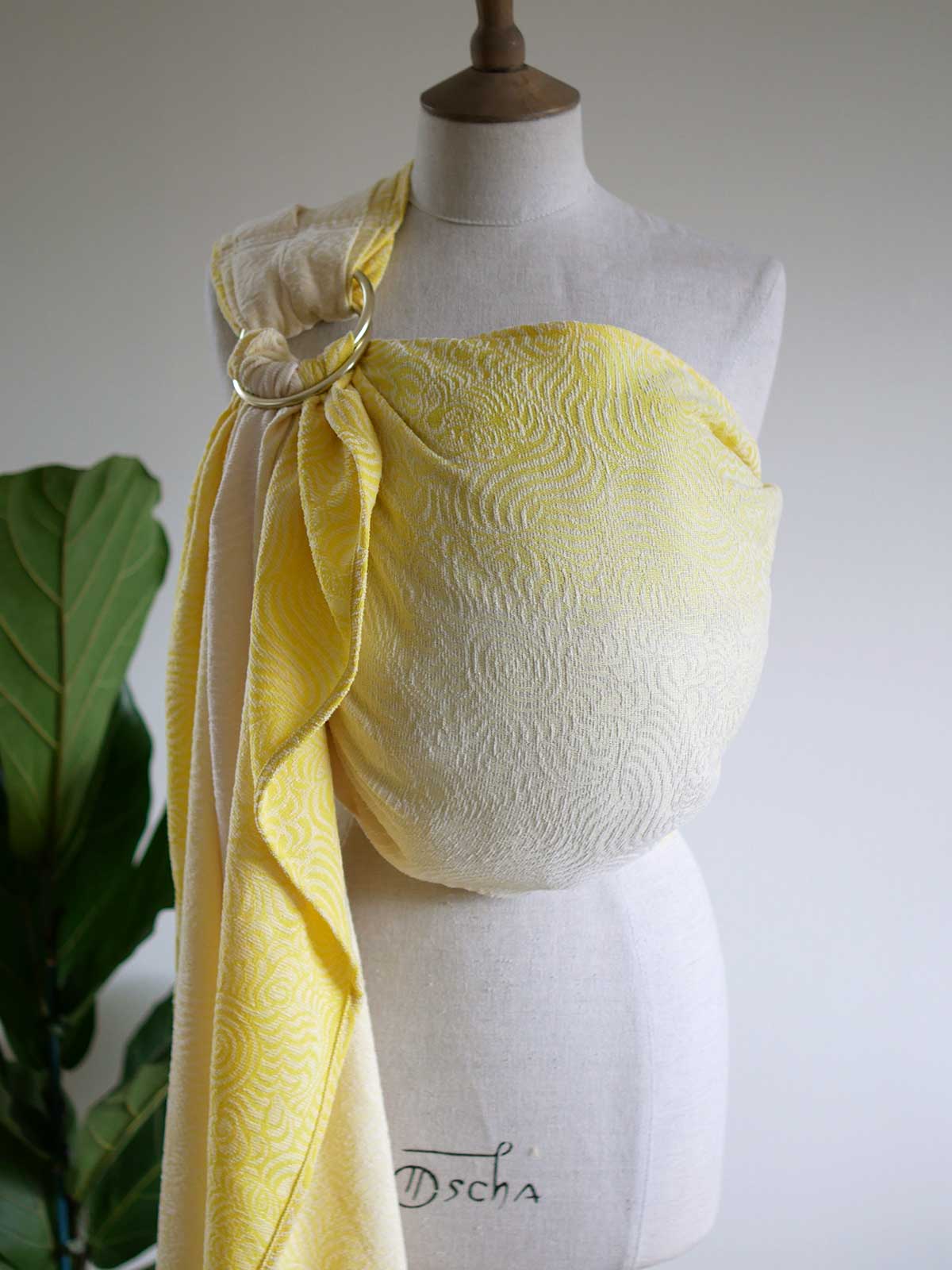 Yellow ring sling on a mannequin with swirling pattern.