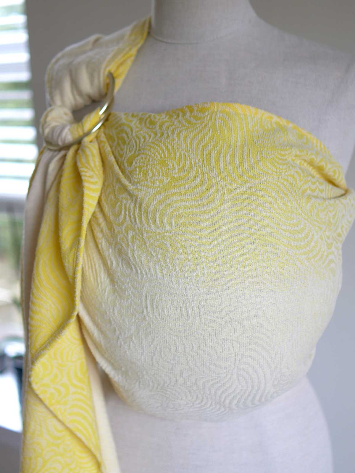 Yellow ring sling on a mannequin with swirling pattern.
