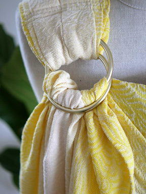 Gold ring on a yellow ring sling on a mannequin.