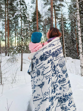 Mum and Baby wrapped in a Realm of Middle-earth blanket in a snowy forest.