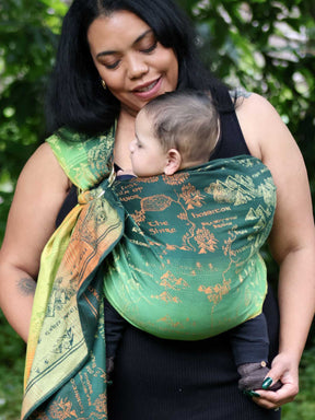 Woman carrying a baby in a green ring sling with map design.
