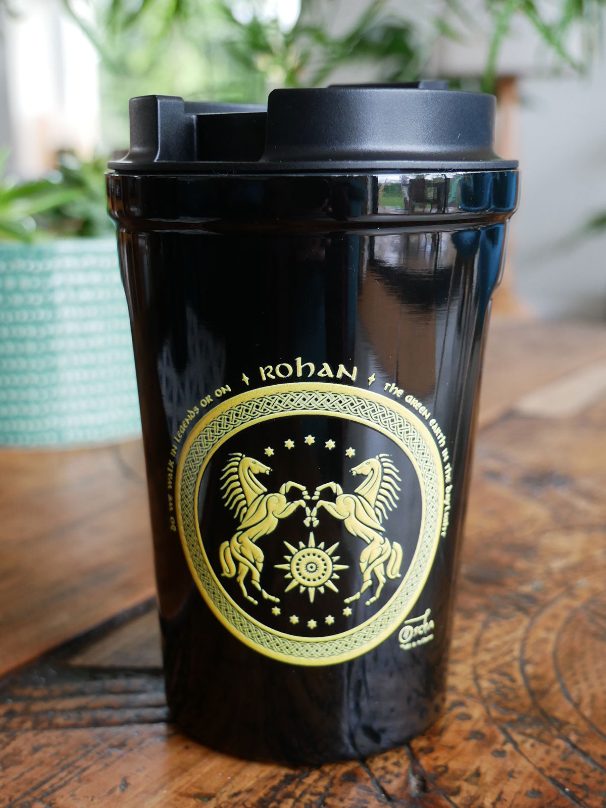 Black travel mug with 'Rohan' branding on a wooden surface