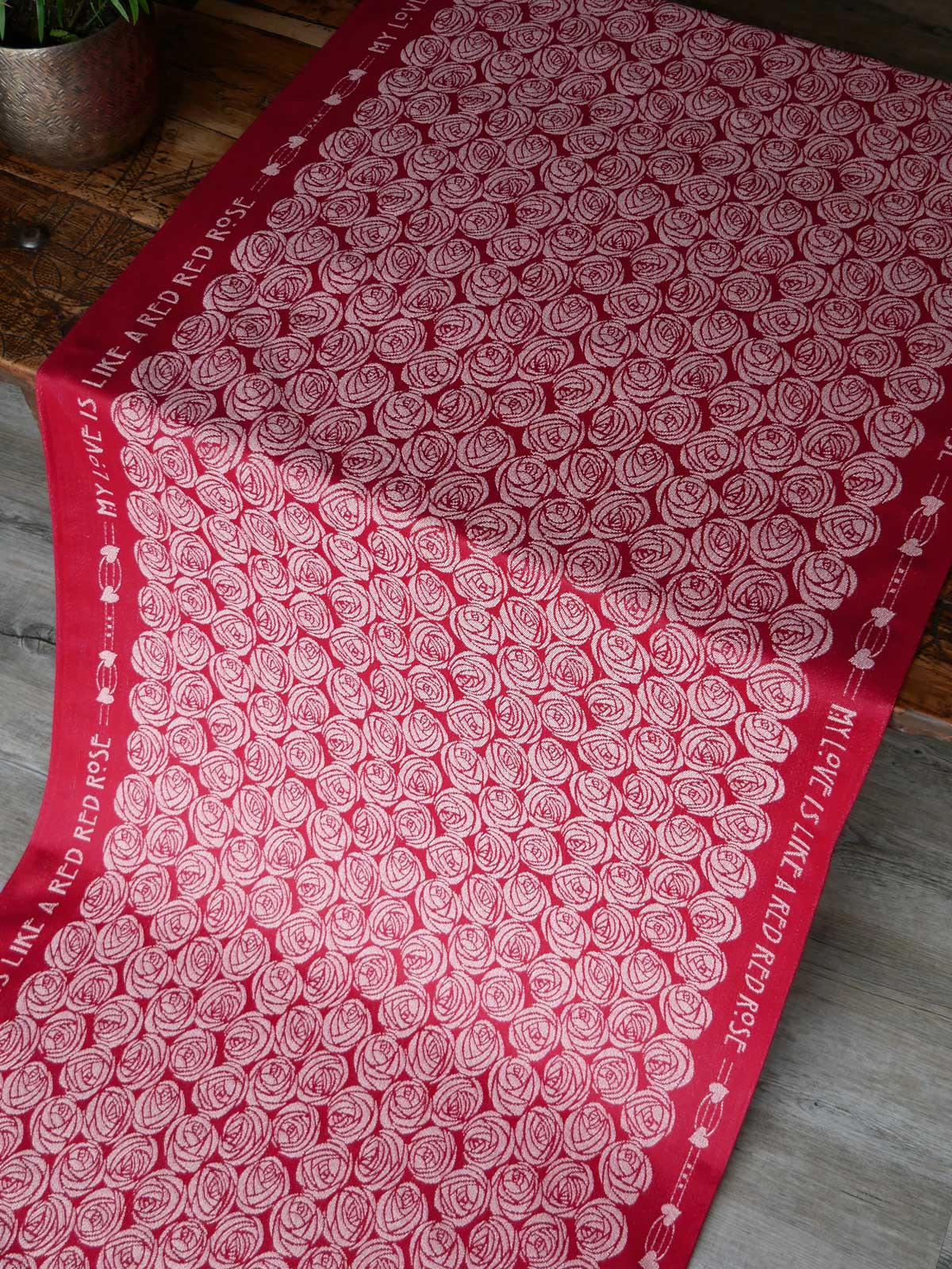 Red fabric with white roses pattern on a wooden surface