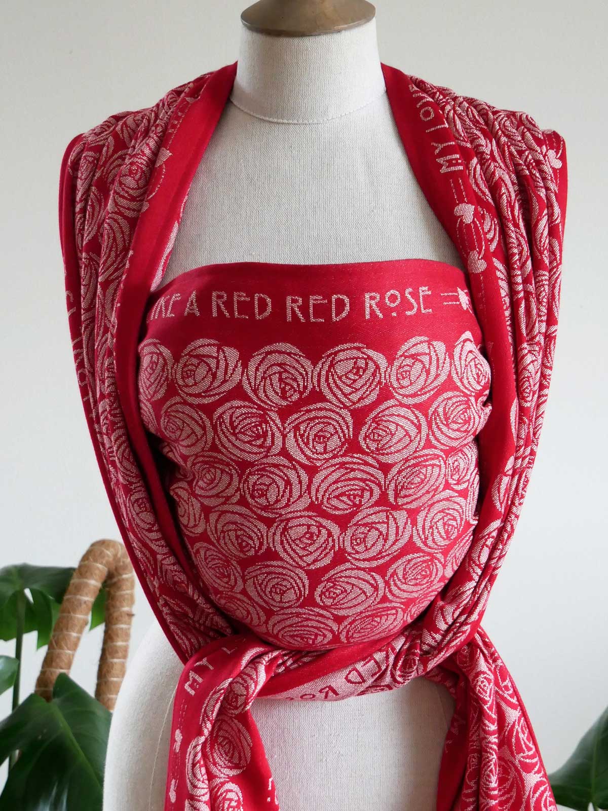 Red woven wrap with white rose pattern draped over a mannequin against a white background