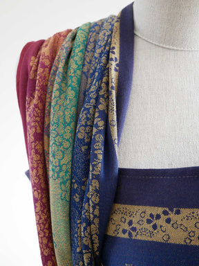 Mannequin wearing a blue fabric with intricate patterns, surrounded by other fabrics in various colours.