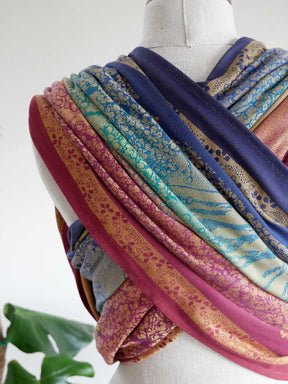 Mannequin wearing a colorful baby wrap with various patterns on a white background