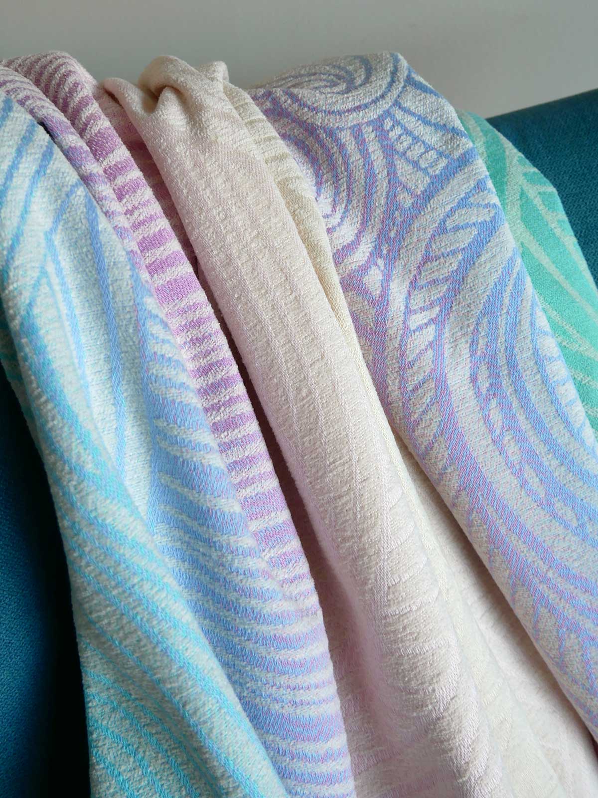 Stack of patterned towels in pastel colors on a blue chair.