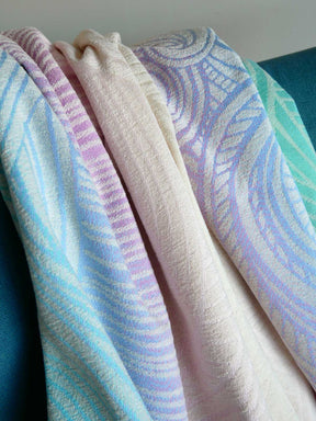 Stack of patterned towels in pastel colors on a blue chair.