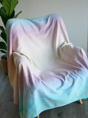 Pastel-colored blanket draped over a chair with a plant in the background