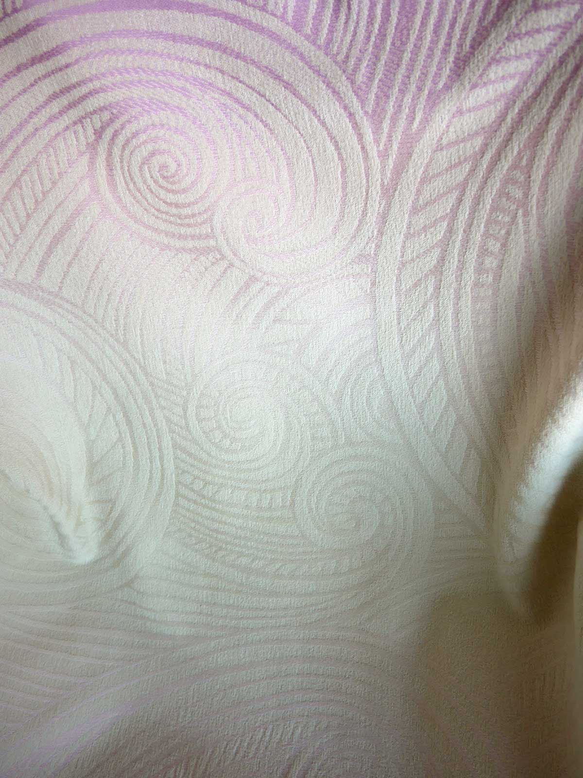 Close-up of textured fabric with circular patterns in light pink and white.