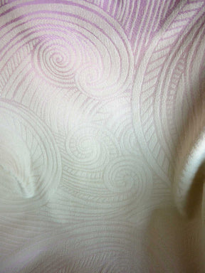 Close-up of textured fabric with circular patterns in light pink and white.