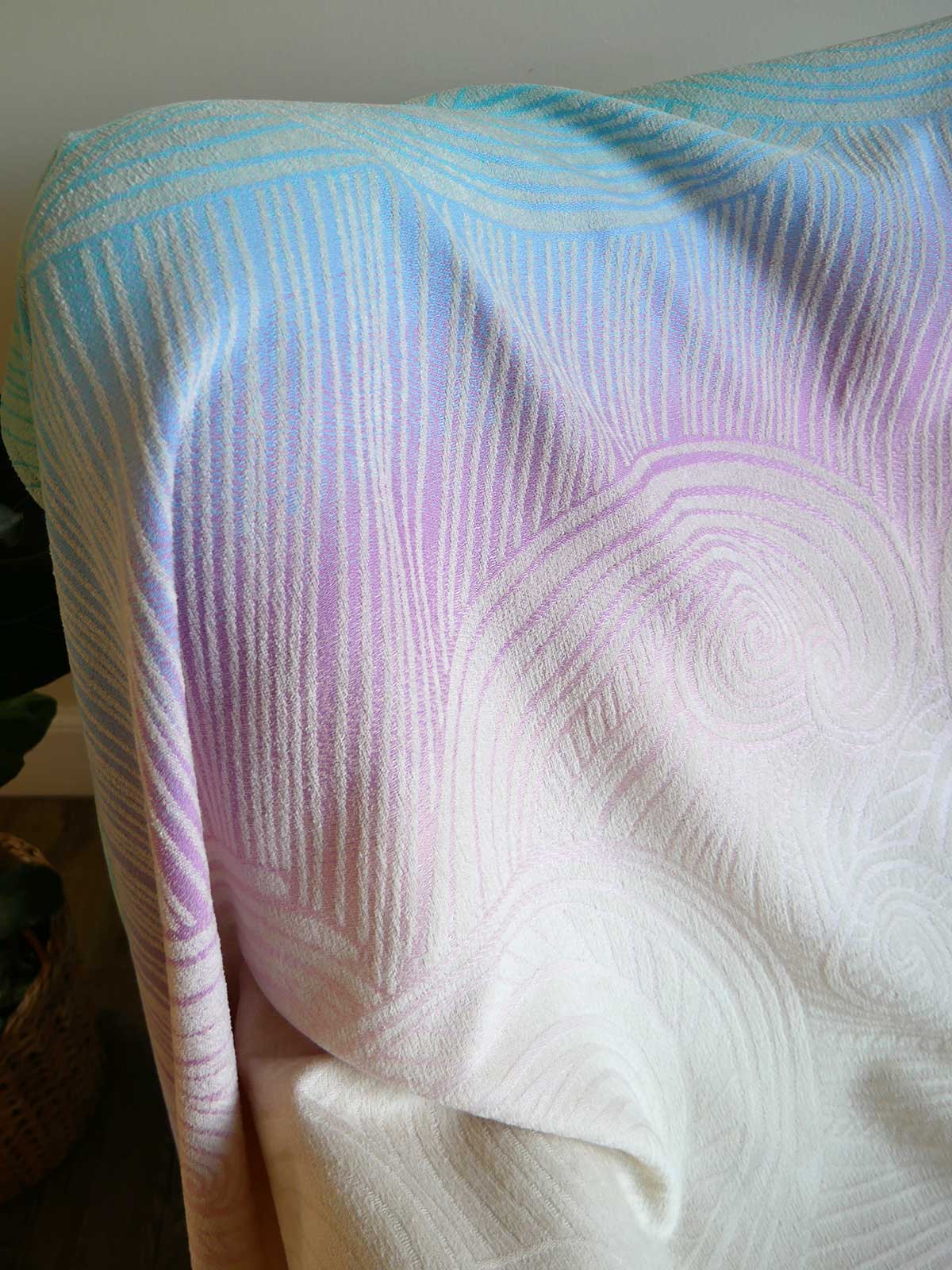 Textured fabric with wavy pattern in white, blue, and purple on a plain background.