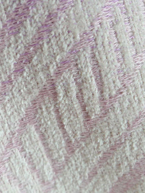Close-up of textured fabric with wavy pattern in pink on beige background