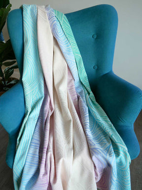Multicolored pastel blanket draped over a blue chair with a neutral background