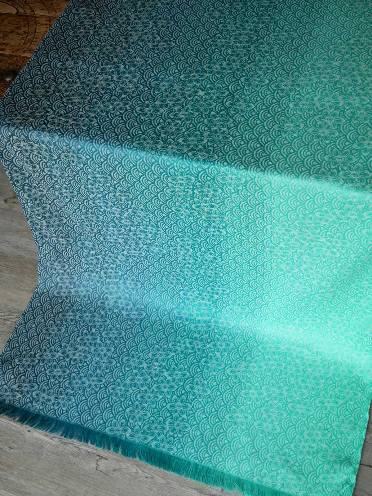 Teal fabric with a subtle pattern on a wooden surface