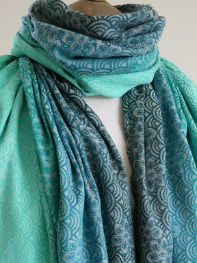 Teal patterned scarf draped over a mannequin on a white background