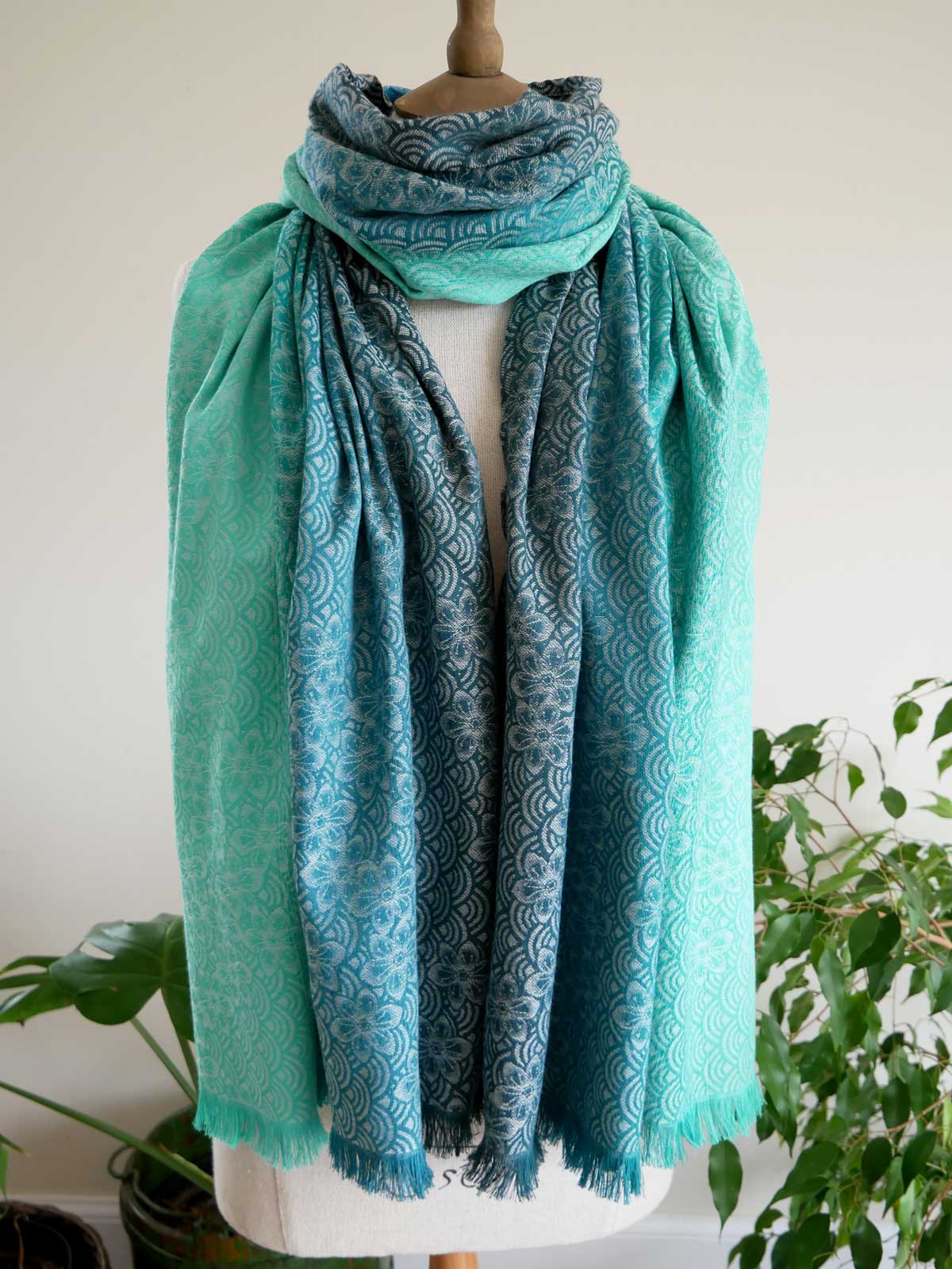 Teal patterned Sekaibloom Wave Scarf on a mannequin with a white background