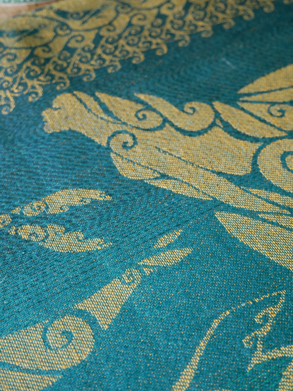 Close-up of teal fabric with gold intricate patterns
