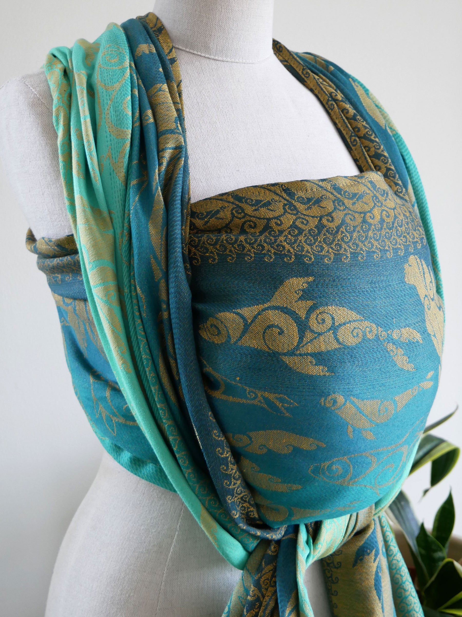Teal and gold Selkies Sounds Baby Wrap draped over a mannequin