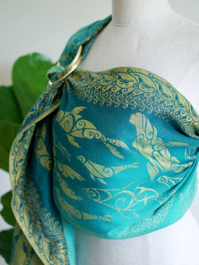 Side view of teal ring sling with gold selkies on a mannequin