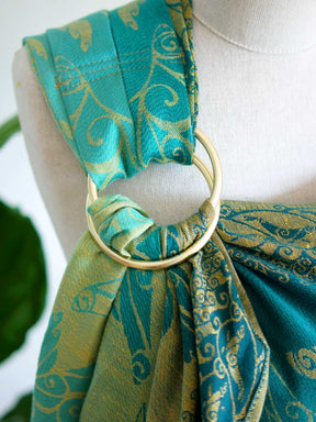 Gold rings on a teal ring sling on a mannequin