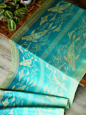Teal fabric with gold selkies on a wooden table