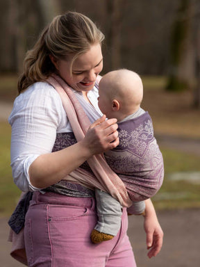 Woman carrying a baby in a sling outdoors