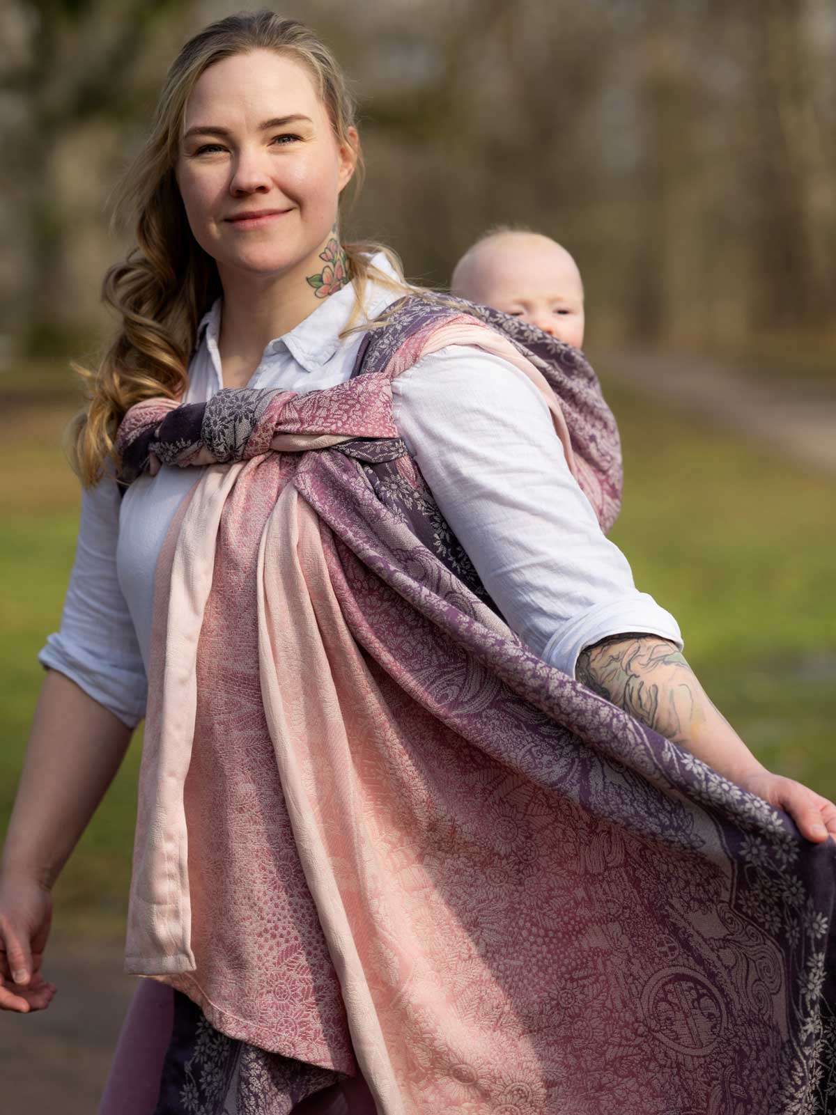 Woman holding a baby in a sling outdoors