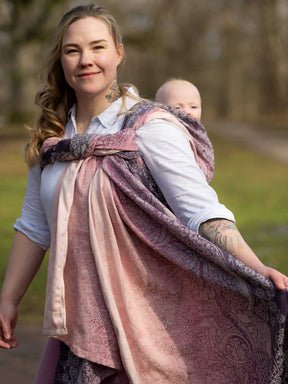 Woman holding a baby in a sling outdoors