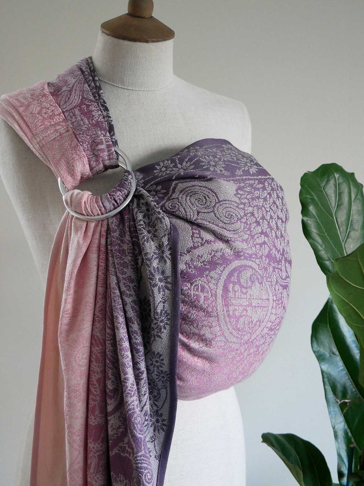 Mannequin wearing a pink and purple patterned ring sling on a white background.