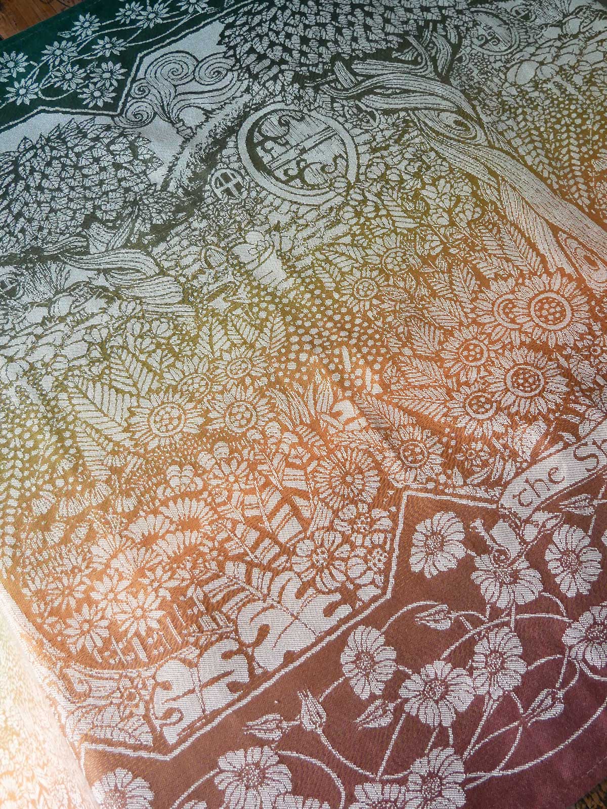 Gradient fabric with floral patterns transitioning from green to brown.