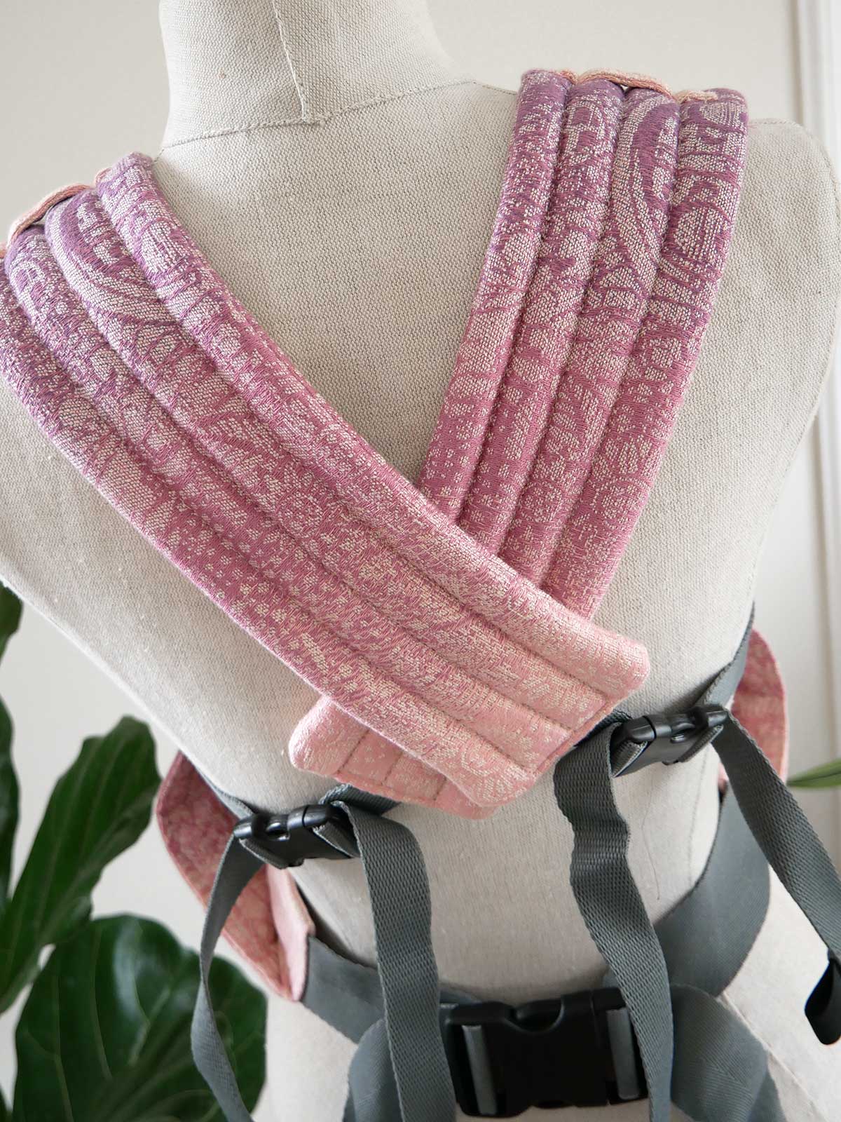 Pink straps of baby carrier on a mannequin with a blurred indoor background